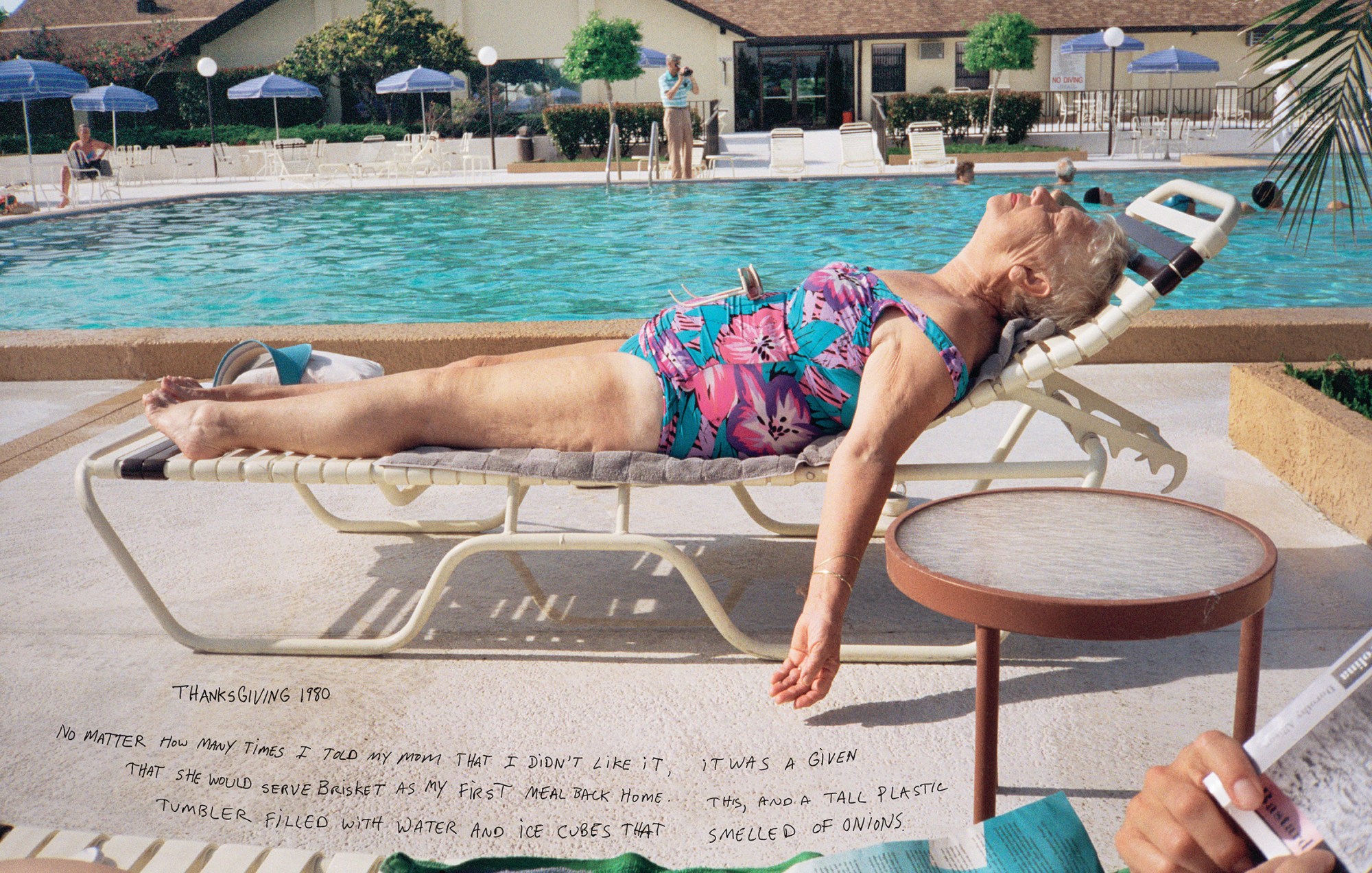 A woman lying in a flower swimsuit on a sunlounger beside a blue swimming pool