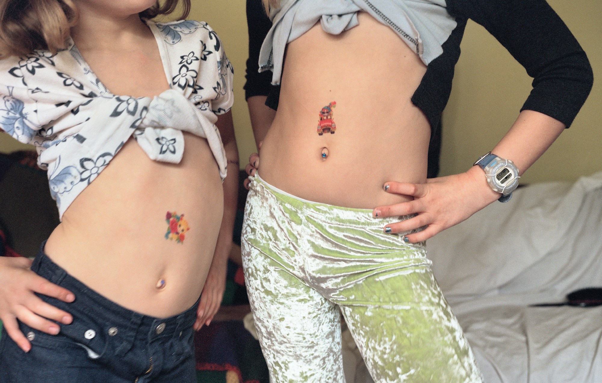 Two young girls with midriffs exposed and temporary colour tattoos on their torsos