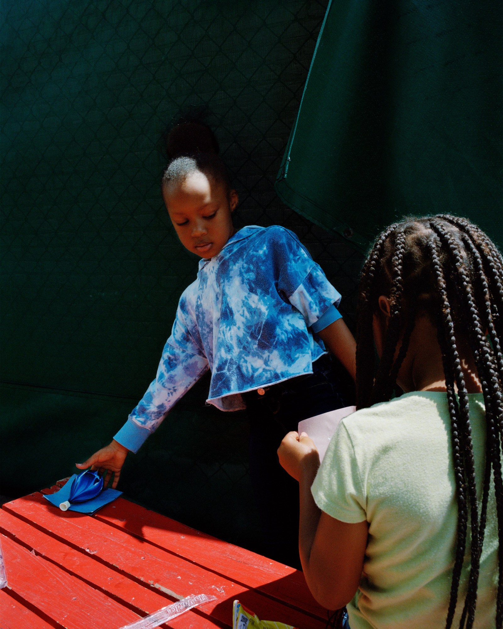 Photograph by Vasantha Yogananthan from Mystery Streets of two girls playing with paper and balloons outside