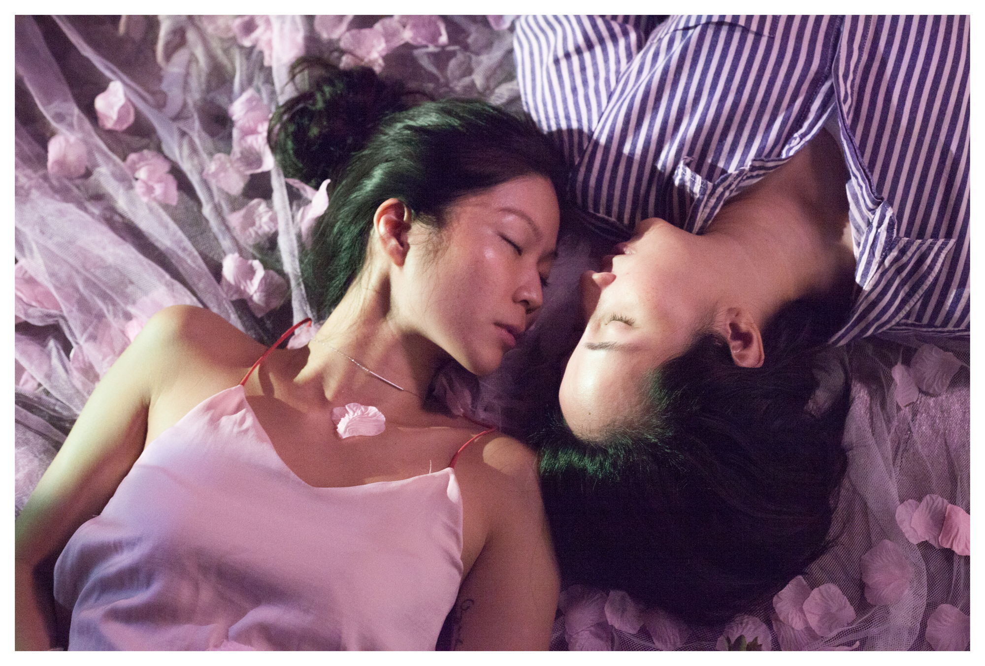 two women lying in bed sprinkled with flower petals