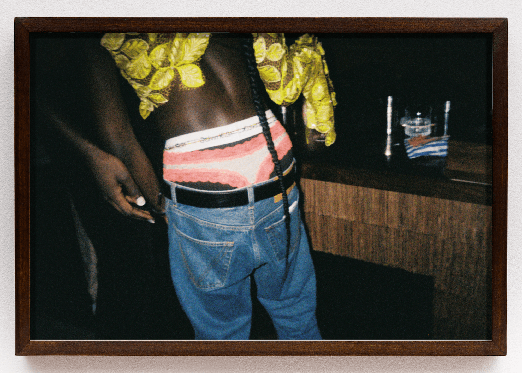 a person wearing black boxers, pink panties, a yello top and belted levis jeans