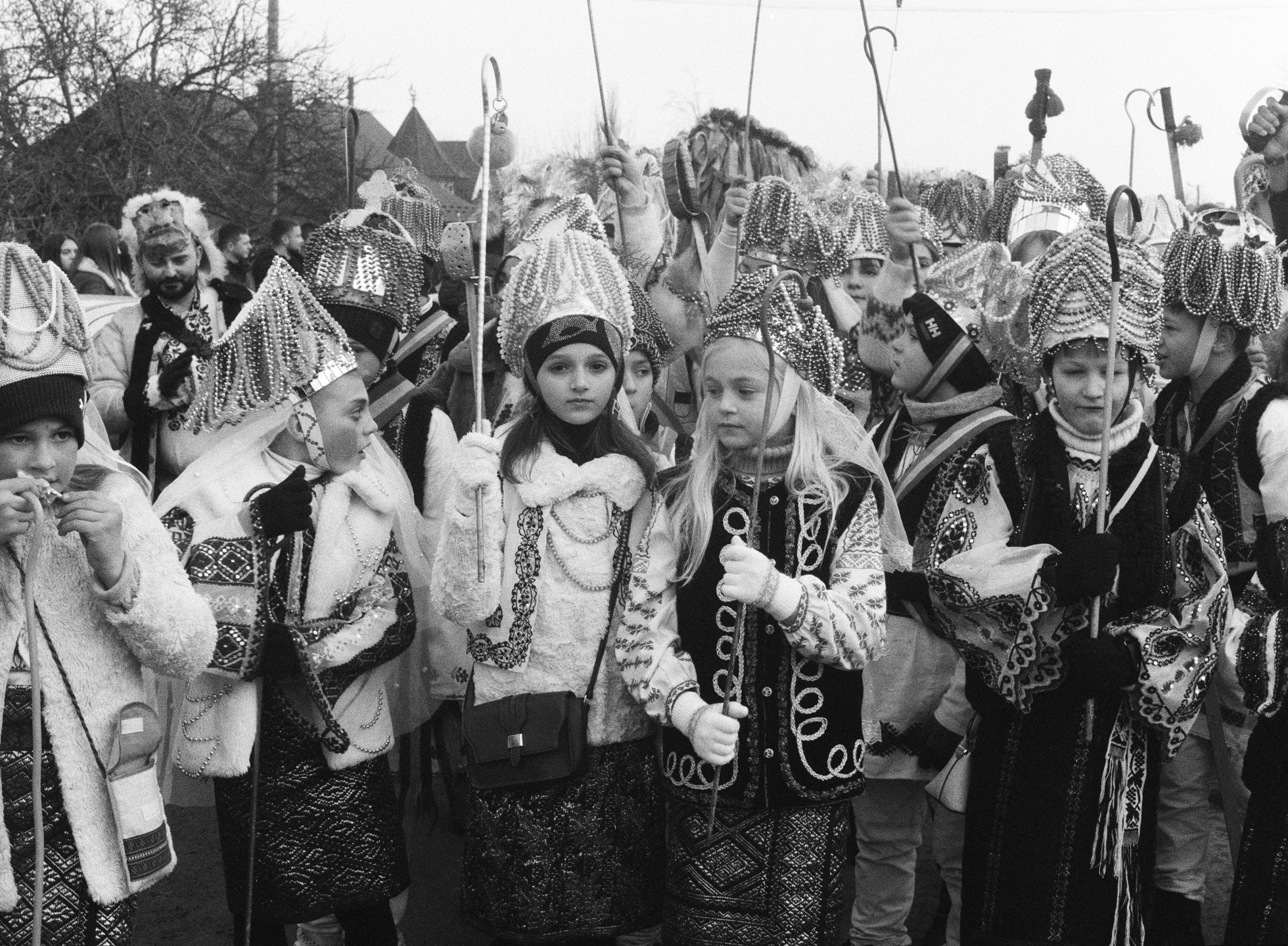 a crowd of young people in homemade saintly costumes featuring pearl-laden crowns and hooked staffs