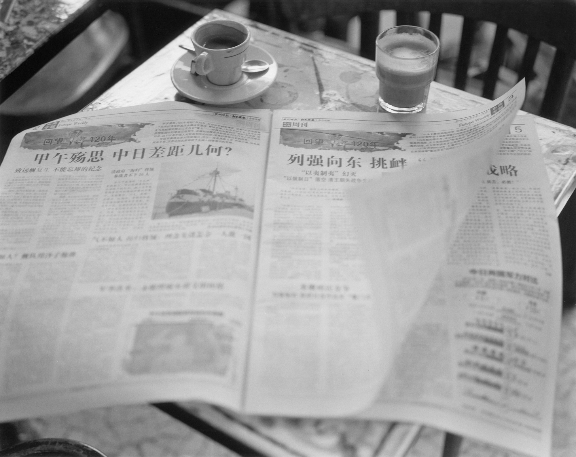 a japanese newpaper laid out on a parisian cafe table