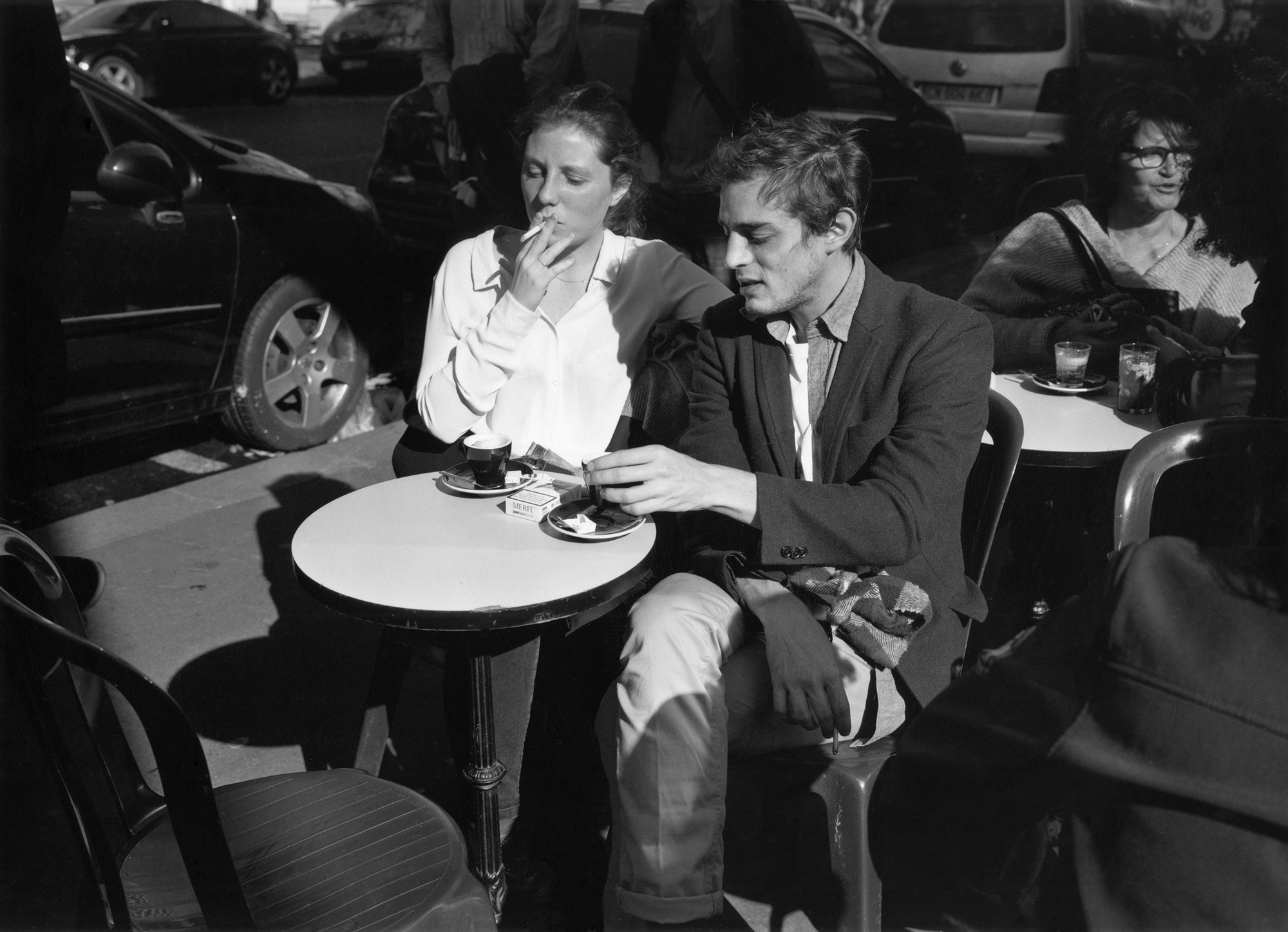 a couple smoking and drinking espresso at a cafe table in paris