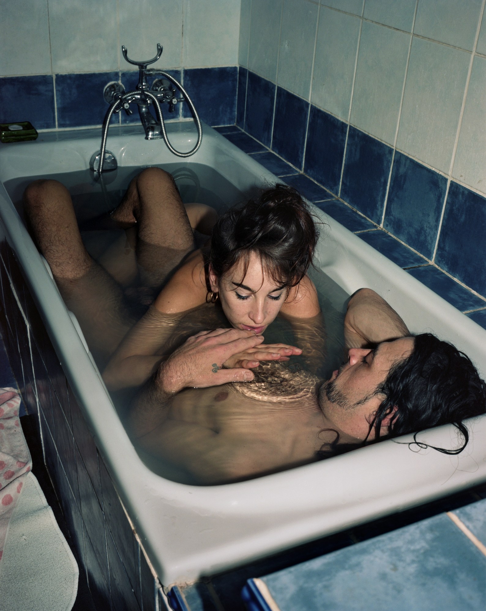 a white couple who look to be in their late 20s cuddle in a small bath