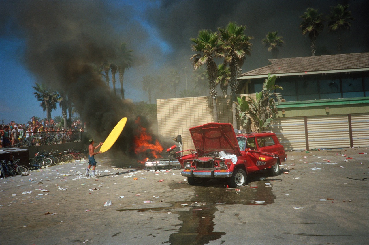 Photograph by Nick Waplington of surfers rioting, burning cars and surfboards.