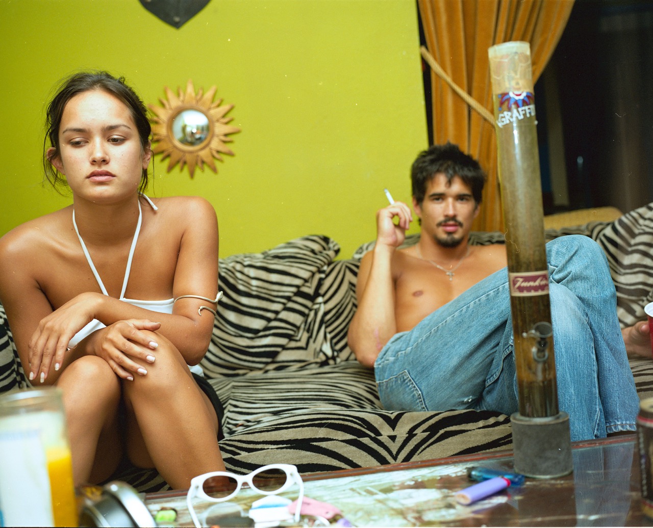 Photograph by Nick Waplington of his friends in the early 1990s sitting on a leopard print sofa with a bong in front of them.