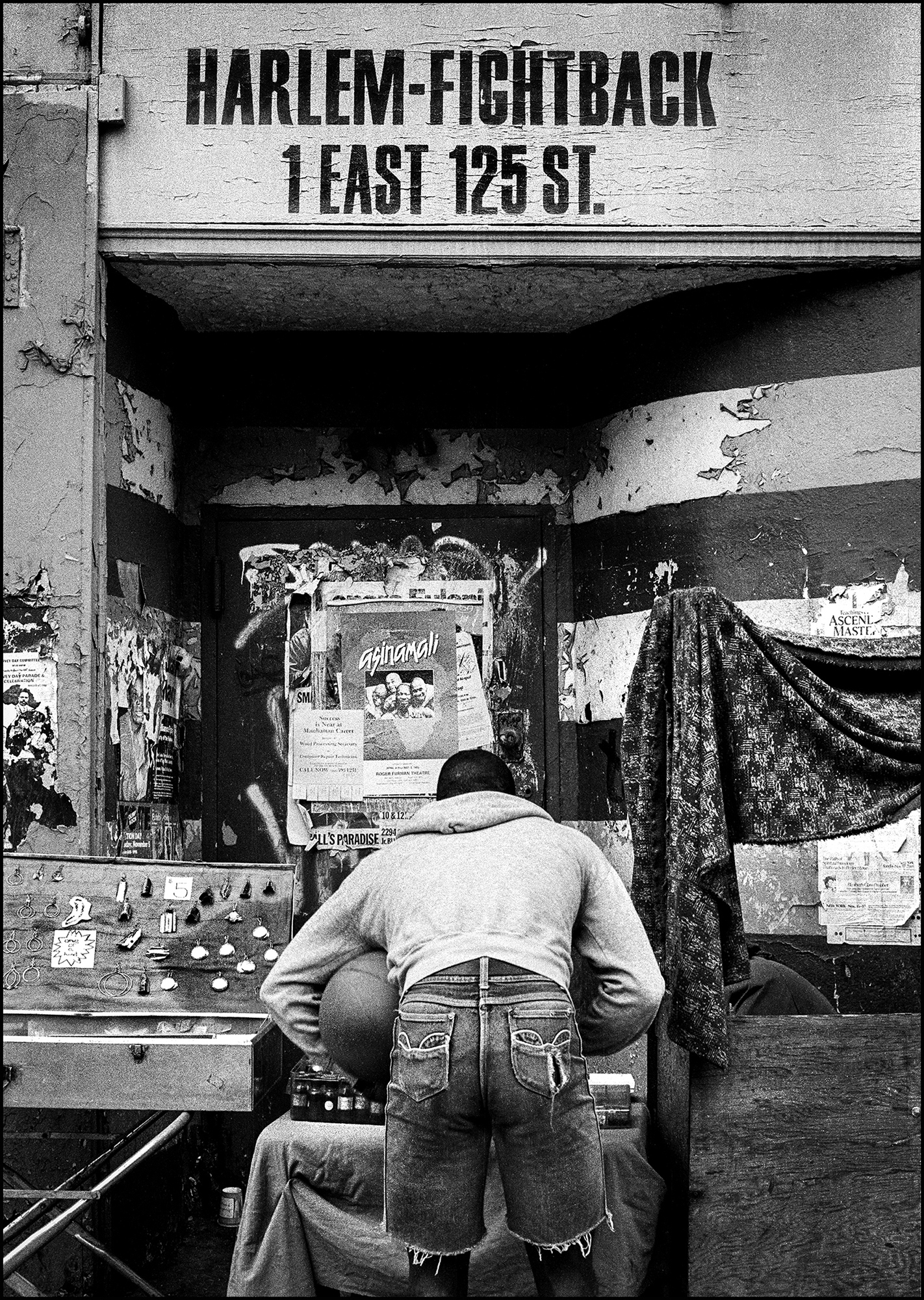 A young man browses trinkets for sale on a Harlem Street stall.