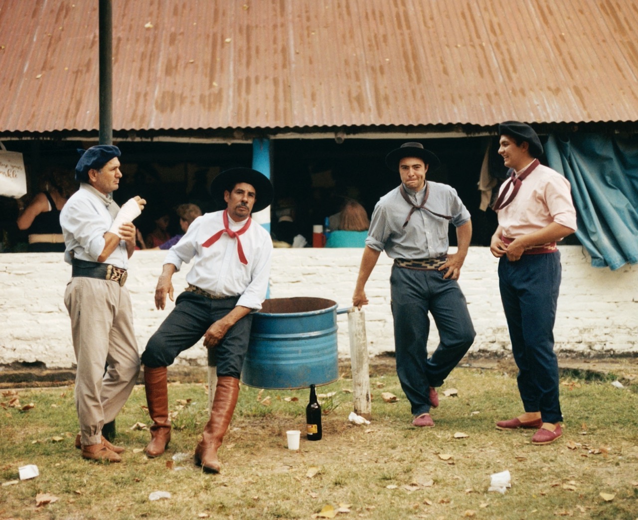 four gauchos hanging out near a blue trash can