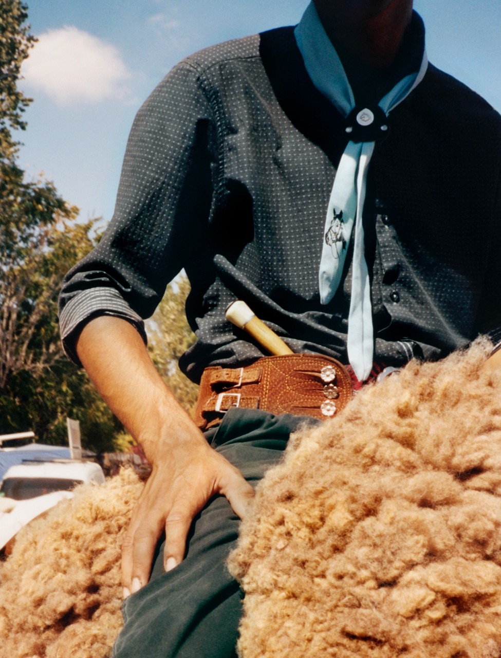 a detail shot of a young gaucho sitting on a fur saddle