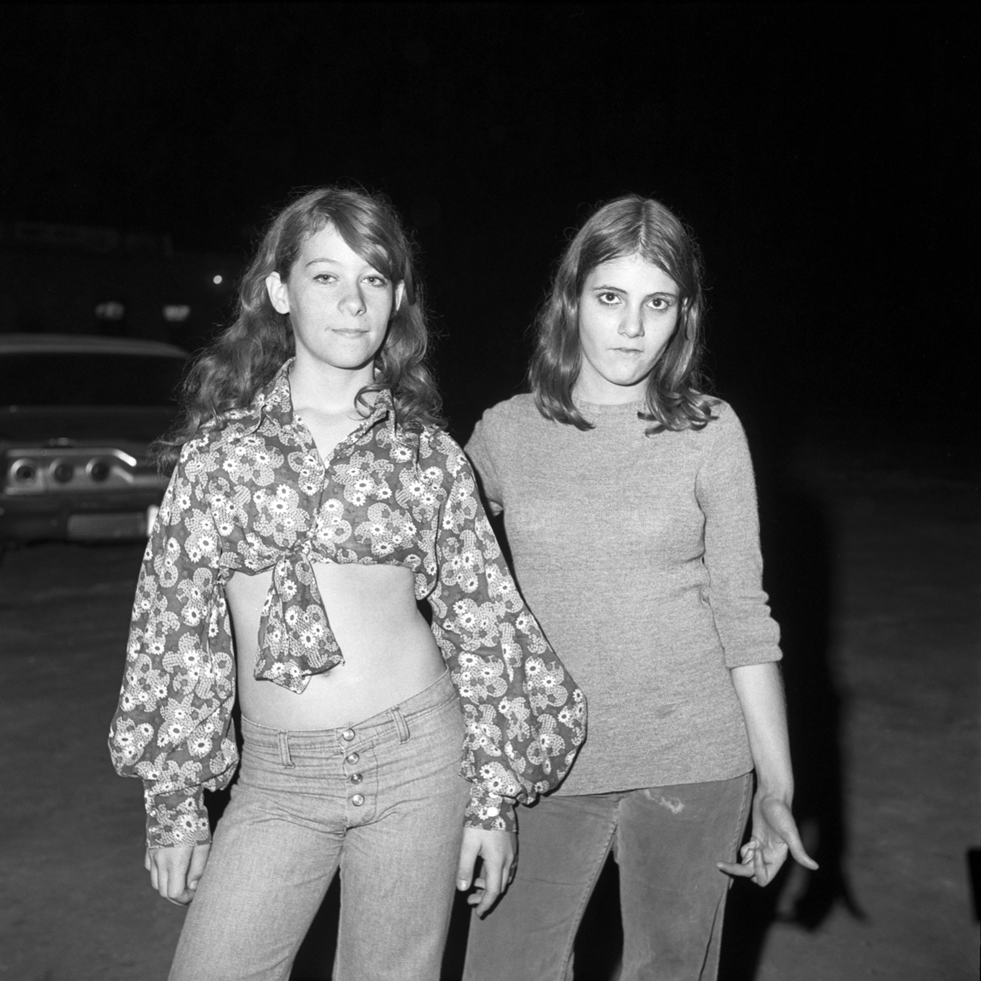 black-and-white image of two teenage girls posing outside of a roller rink in 1970s tampa