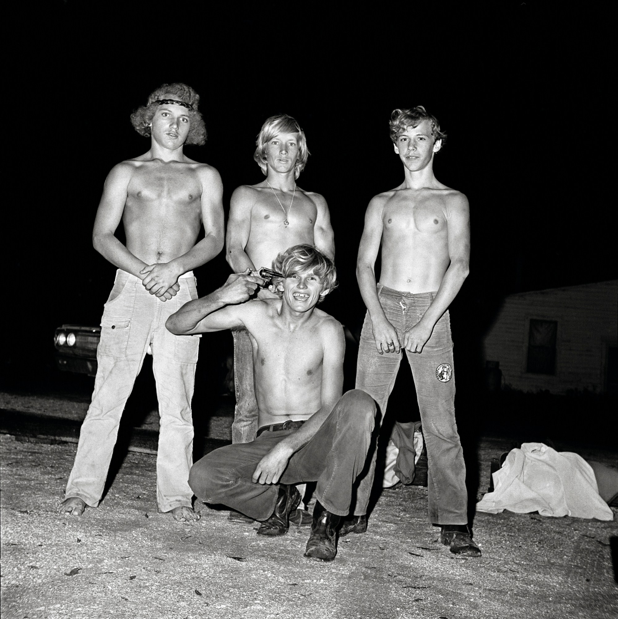 four topless teenage boys pose with a gun outside a 1970s roller rink in florida