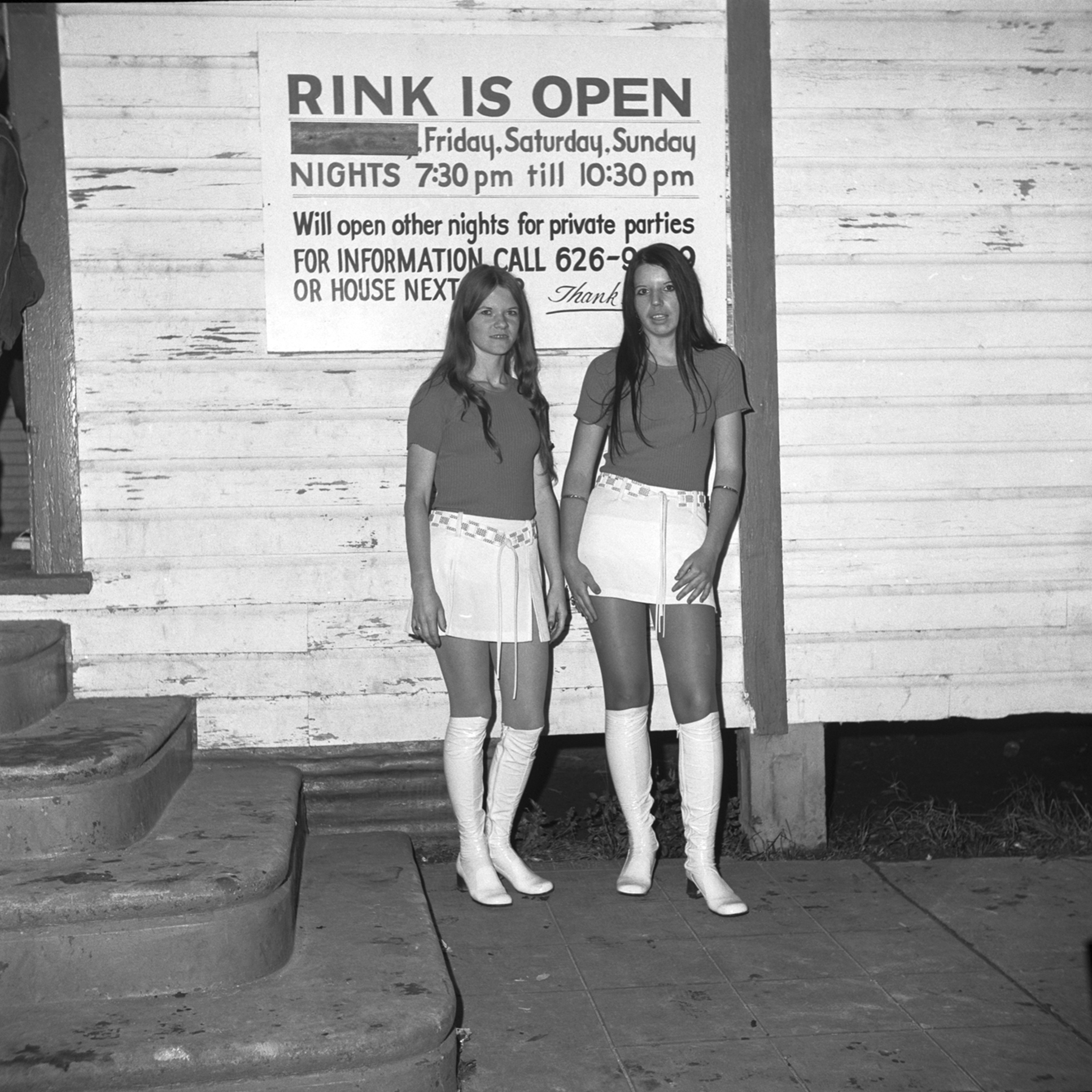 black-and-white image of two teenage girls in white go go boots outside a roller rink in 1970s florida