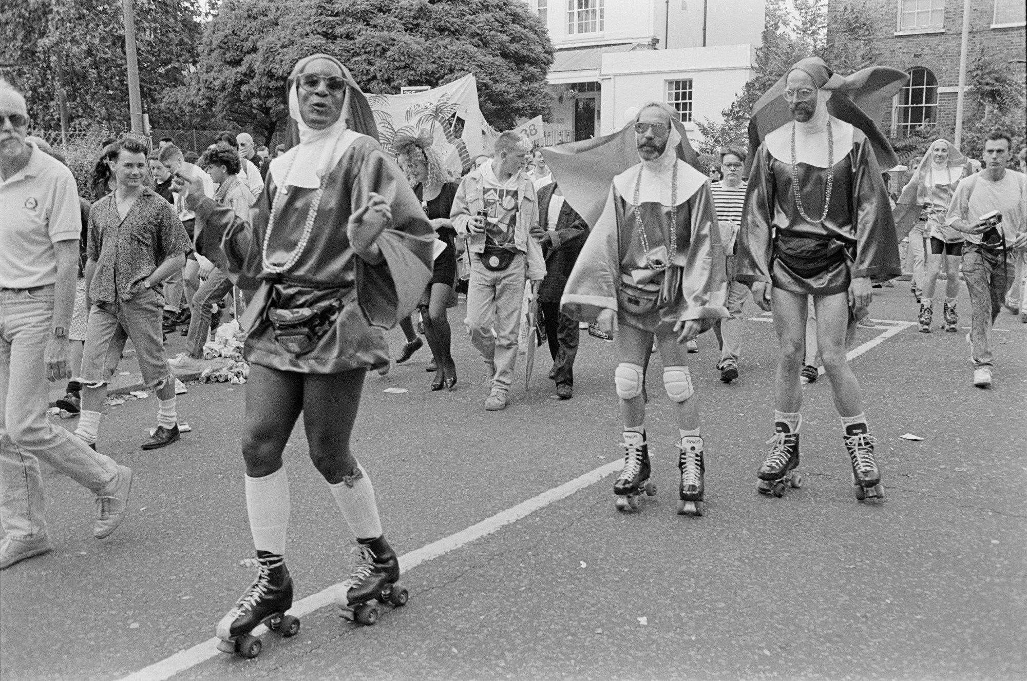 a group queer protestors dressed in short nun outfits skate towards the camera