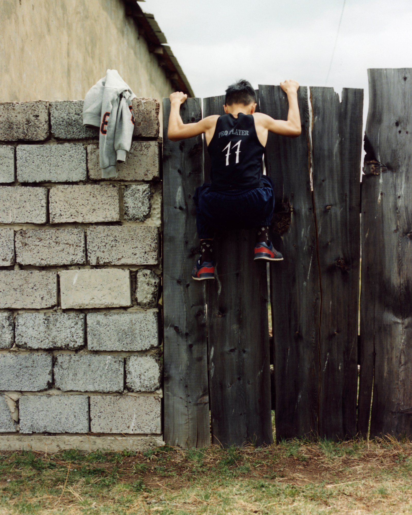 a young boy climbing a wooden fence