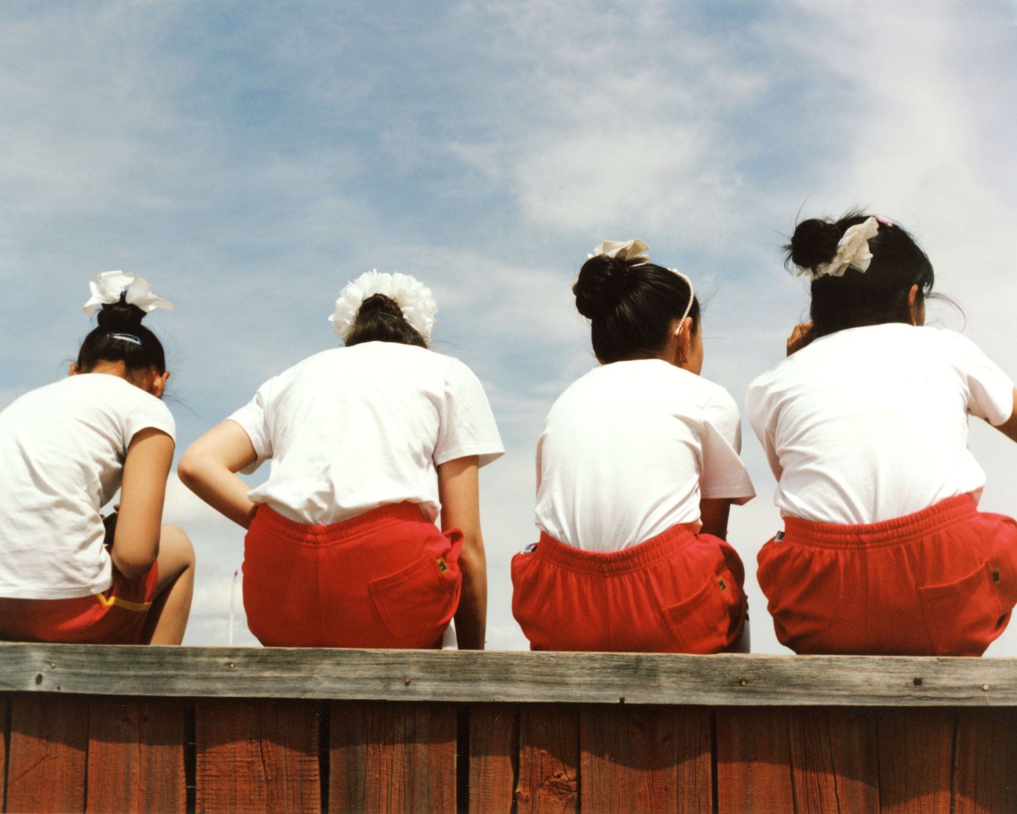 four young girls in red shorts, white t-shirts and white bow barettes