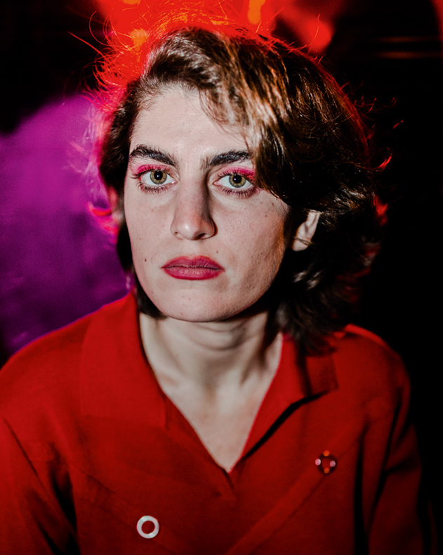 a young woman with short brown hair in a red collared shirt looking at the camera