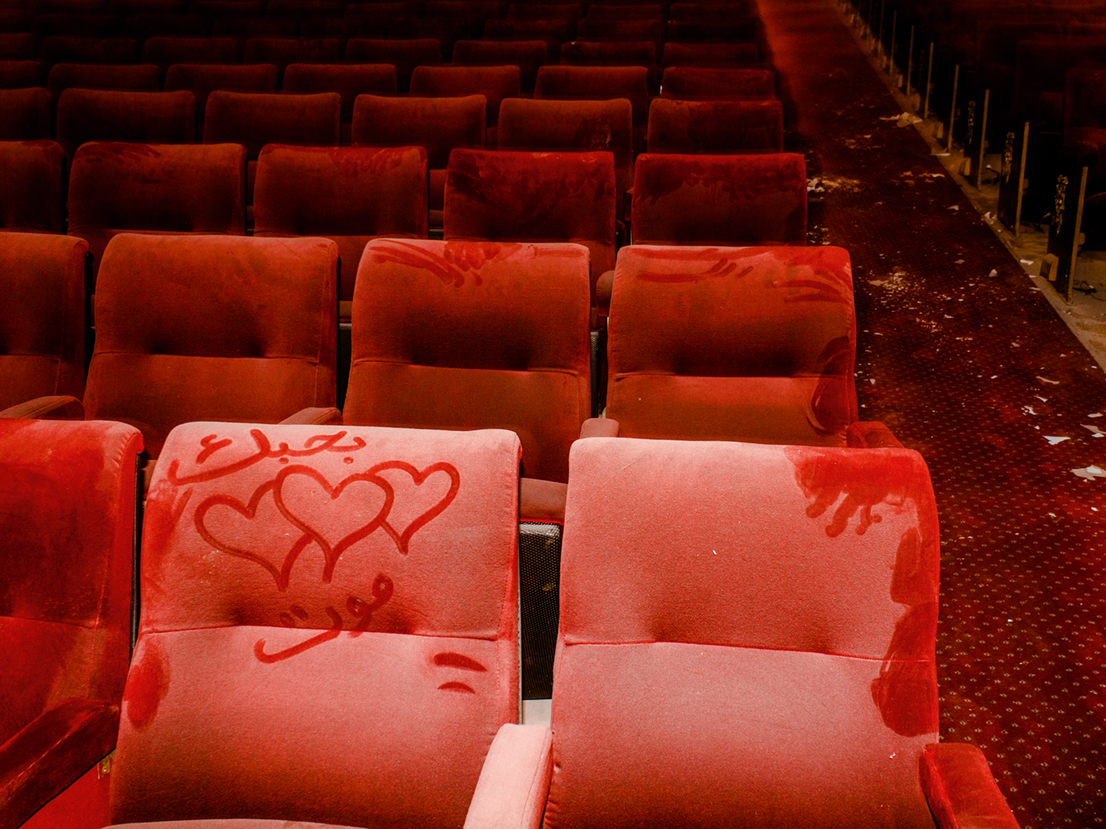 red handprints and heart graffiti on pink seats in a deserted cinema in lebanon