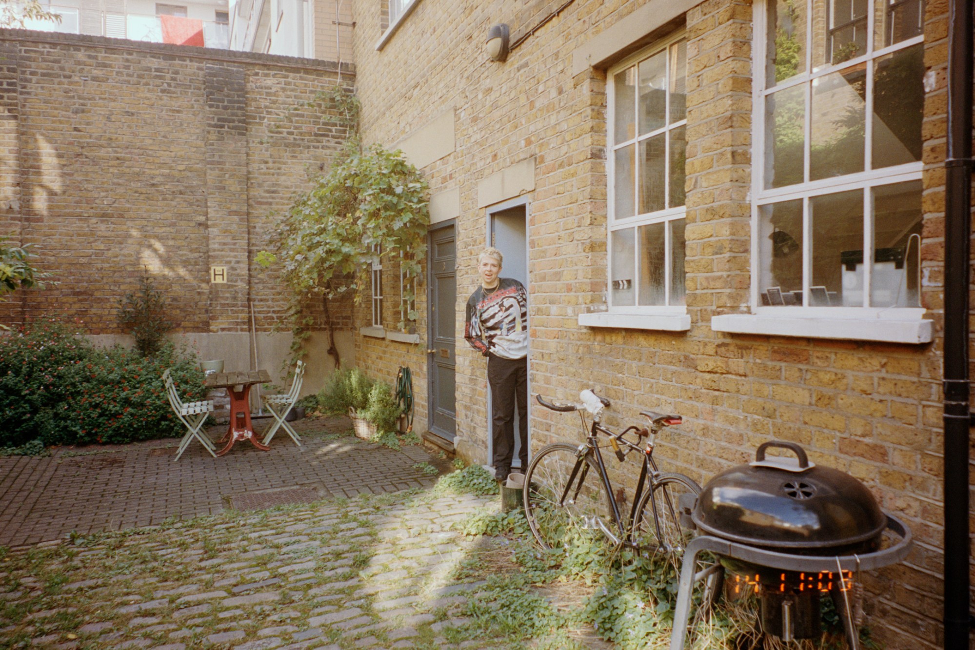 molly manning walker standing in the doorway of her mews studio apartment, smiling to camera