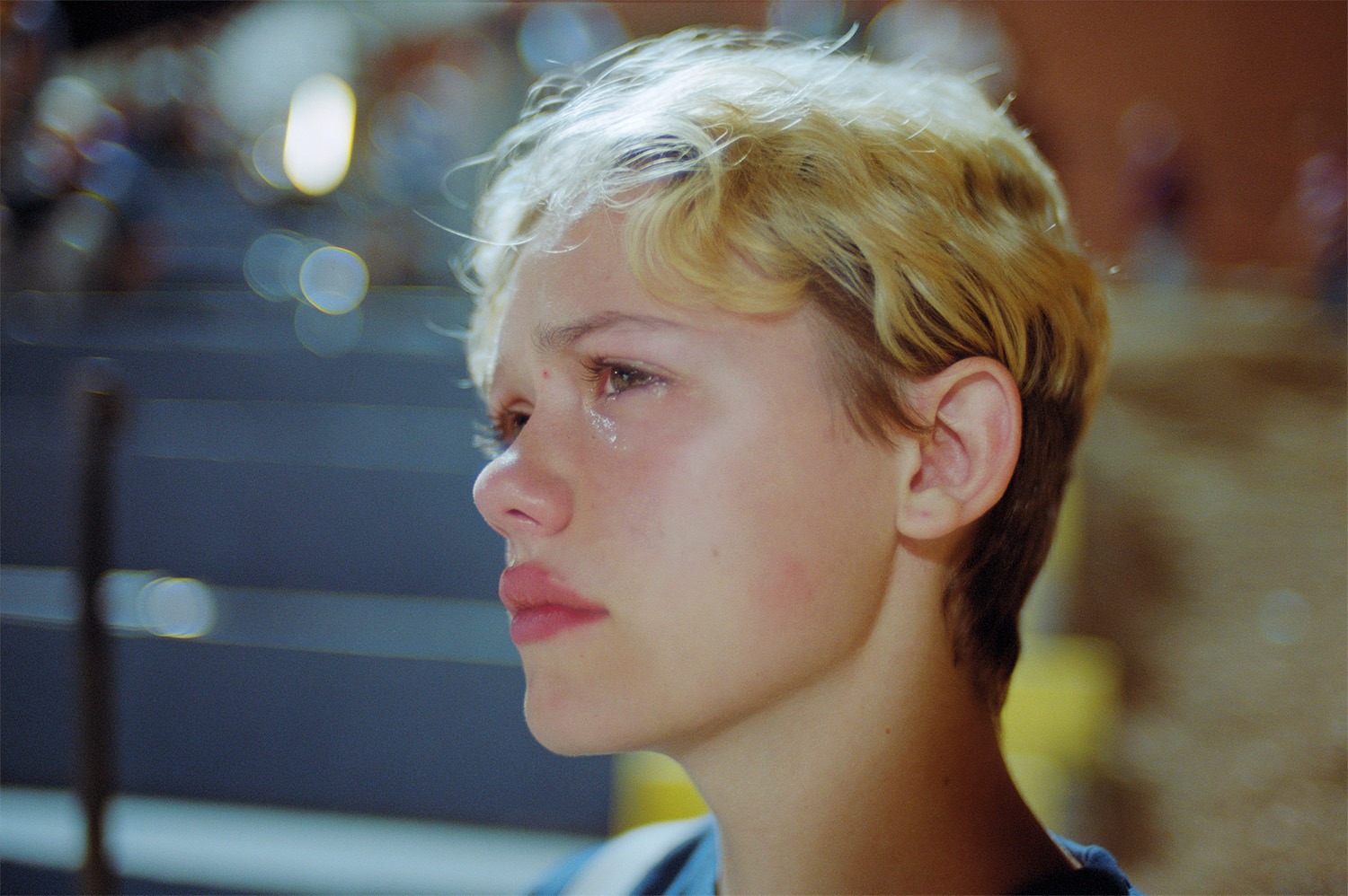 a woman with short bleached blonde hair cries and looks into the distance