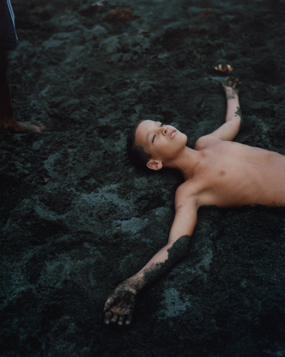 a young boy playing in black sand