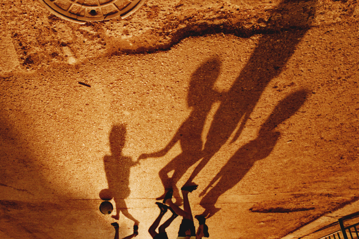 young children playing soccer casting long shadows