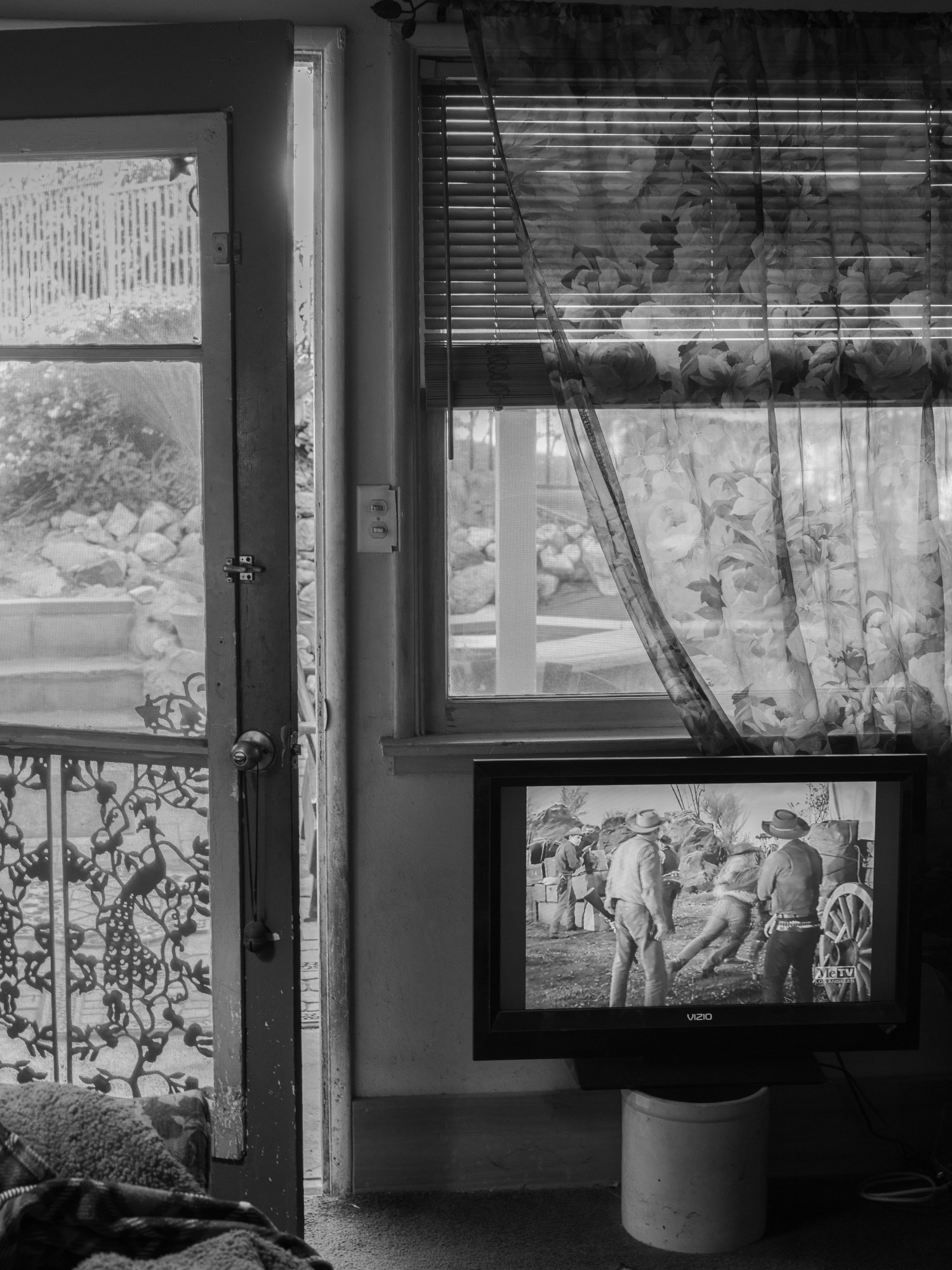 an open door and windows with a western playing on the television