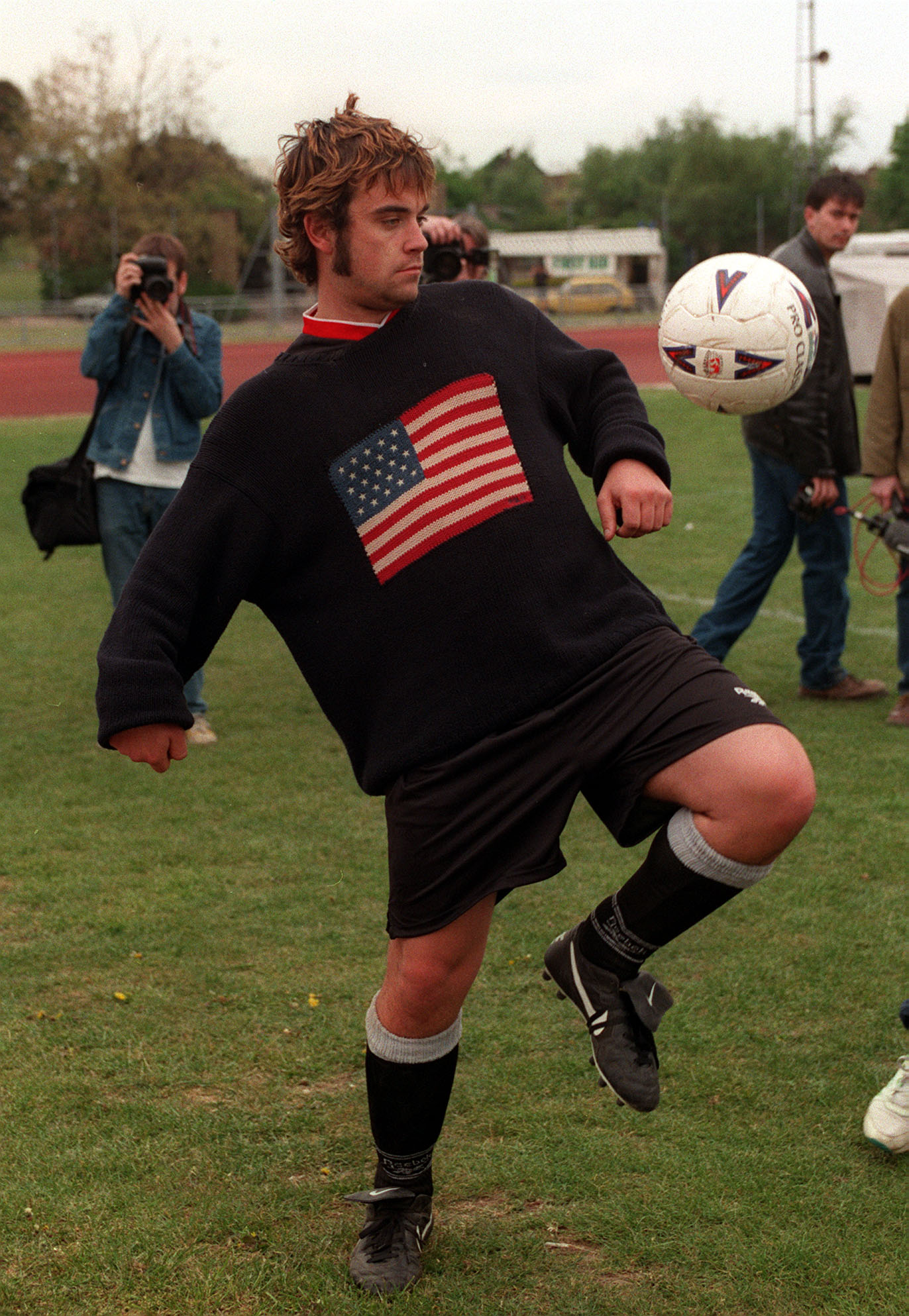 robbie williams in 1996 kicking a football at a charity match