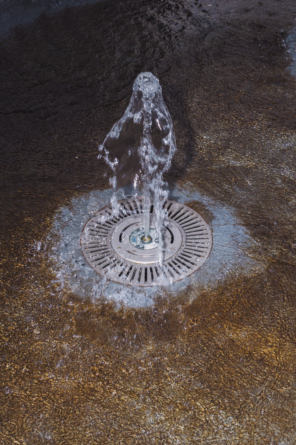 a close up of a water fountain in a shallow pool