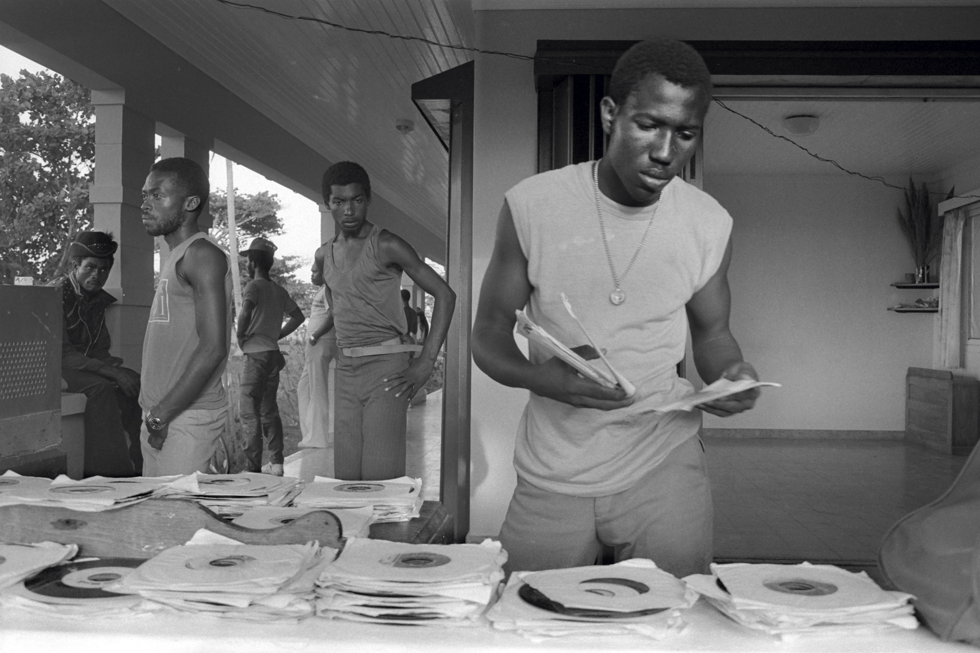 a man in a sleeveless tshirt sorting through a pile of vinyl records