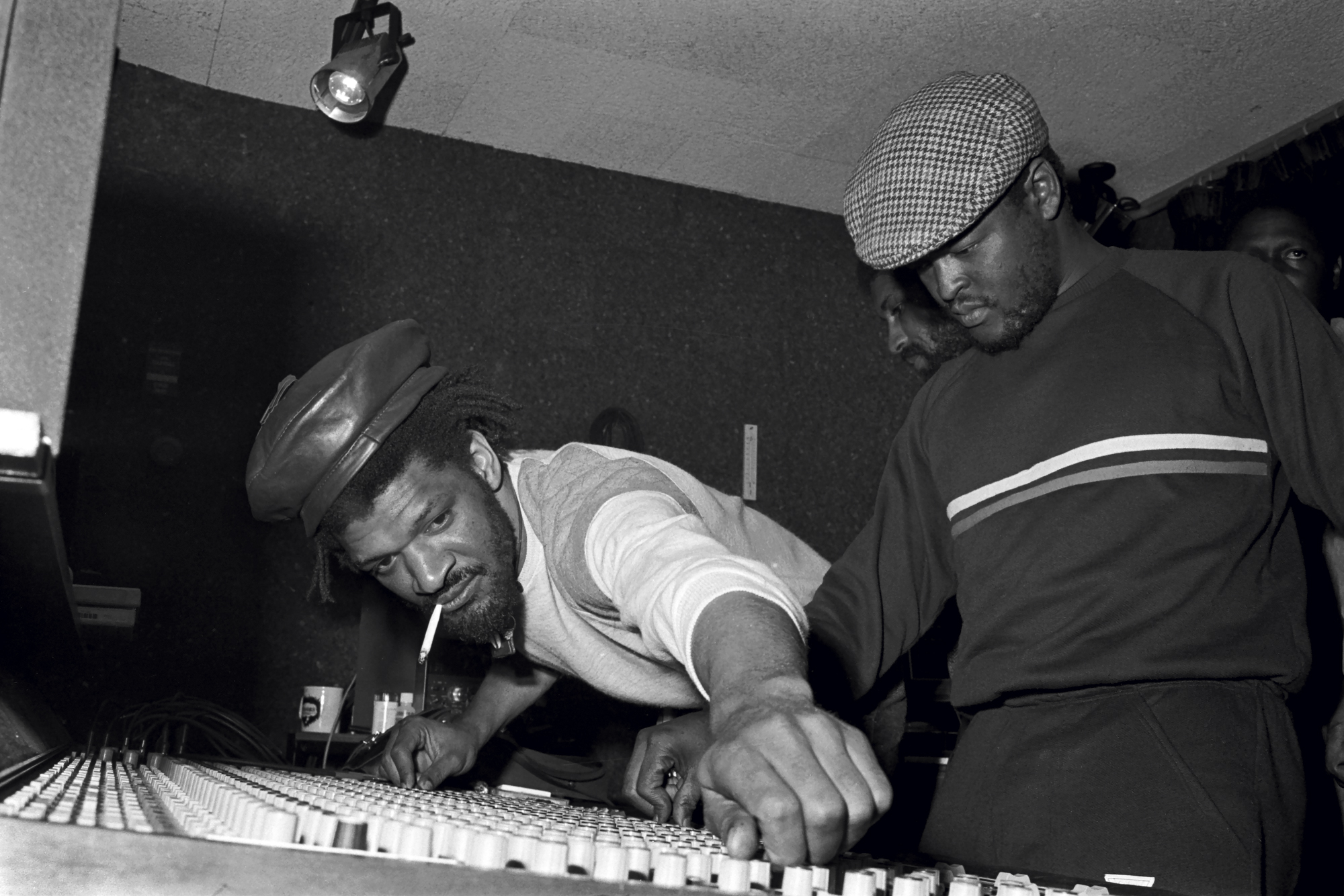 two djs wearing hats and adjusting levels in a studio