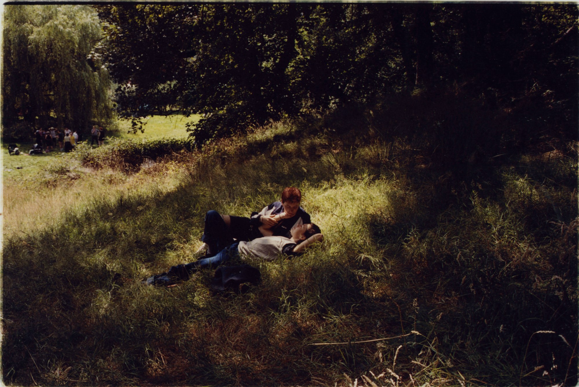 two people lounge about in the dappled sunlight of a meadow