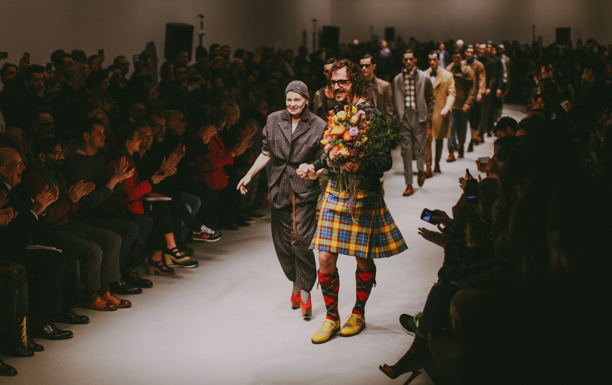 vivienne westwood and andreas kronthaler walking down the runway together with flowers