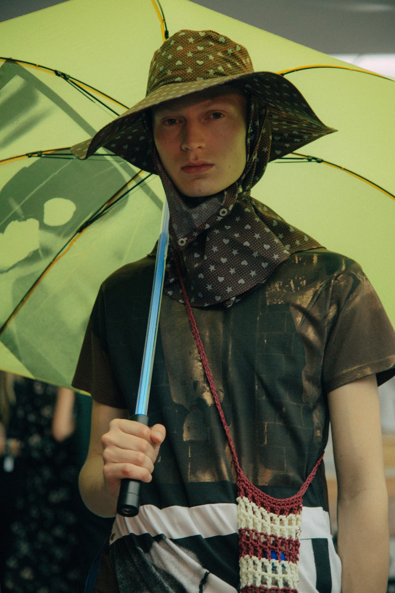 A model carrying a yellow umbrella and wearing a hat at Raf Simons SS18