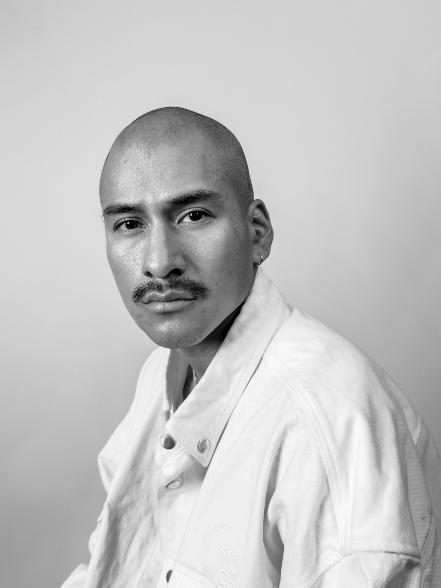 Black-and-white headshot of a man in a white denim jacket