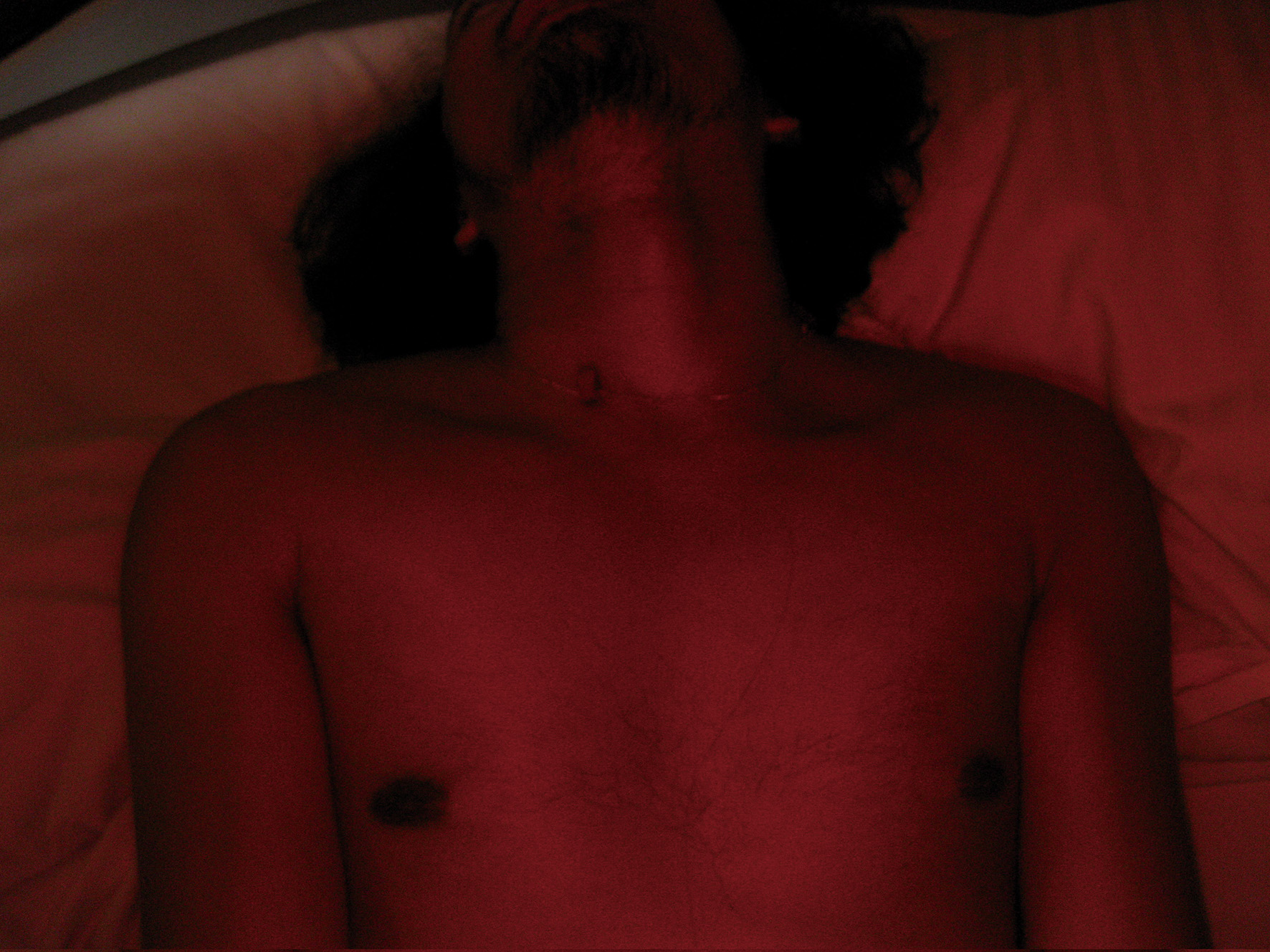 man with a bare chest lying down in red light