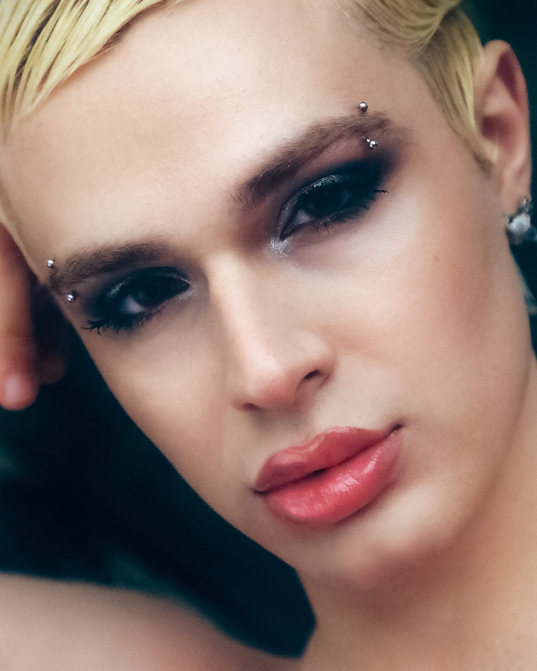 a headshot of the DJ babynymph with glossy lips, heavy eyemakeup and pierced eyebrows