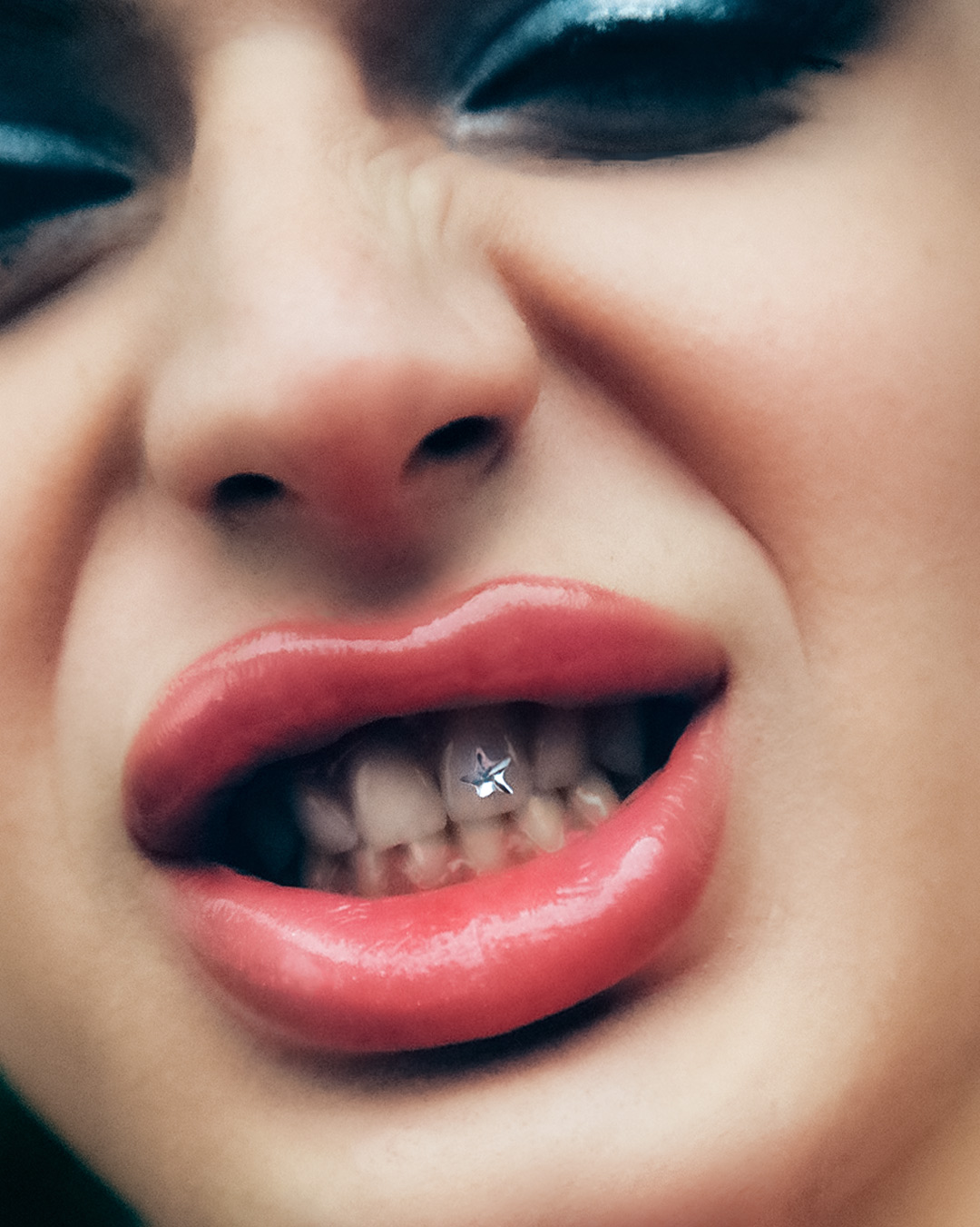 a headshot of the DJ babynymph with glossy lips, parted to reveal a silver star-shaped tooth gem