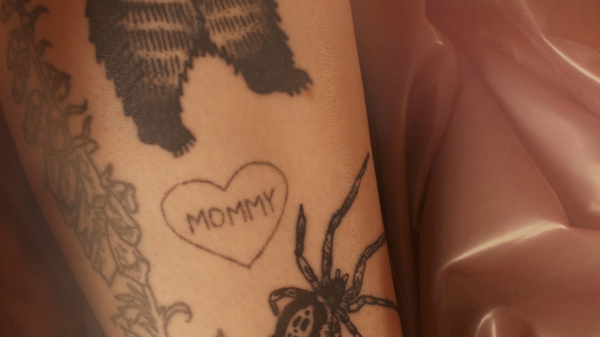 a heart tattoo reading mommy on a pink background