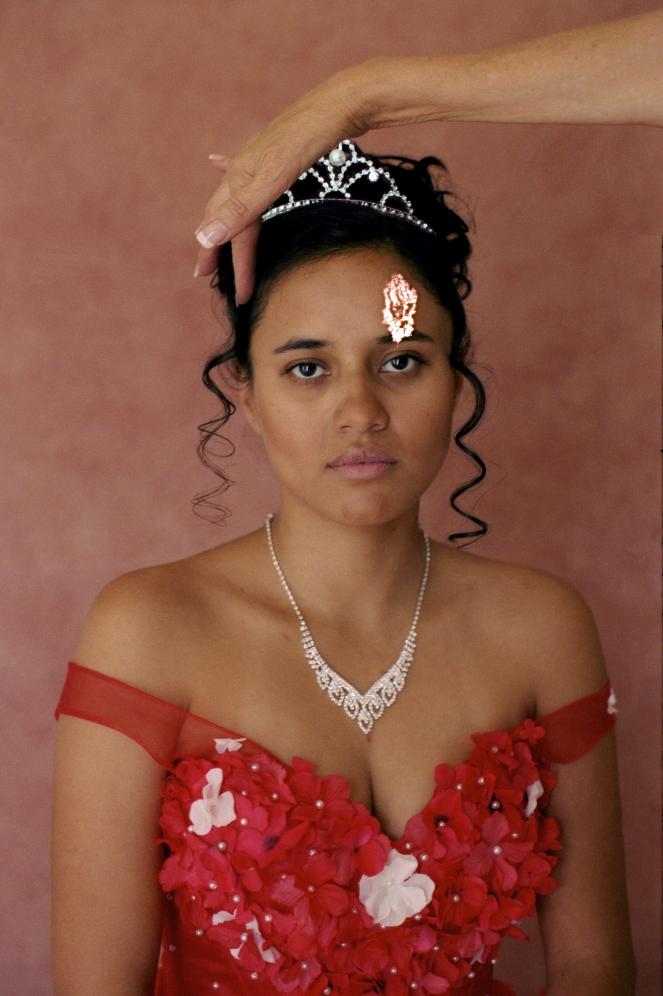 a girl in a quincinera dress with diamond necklace and tiara