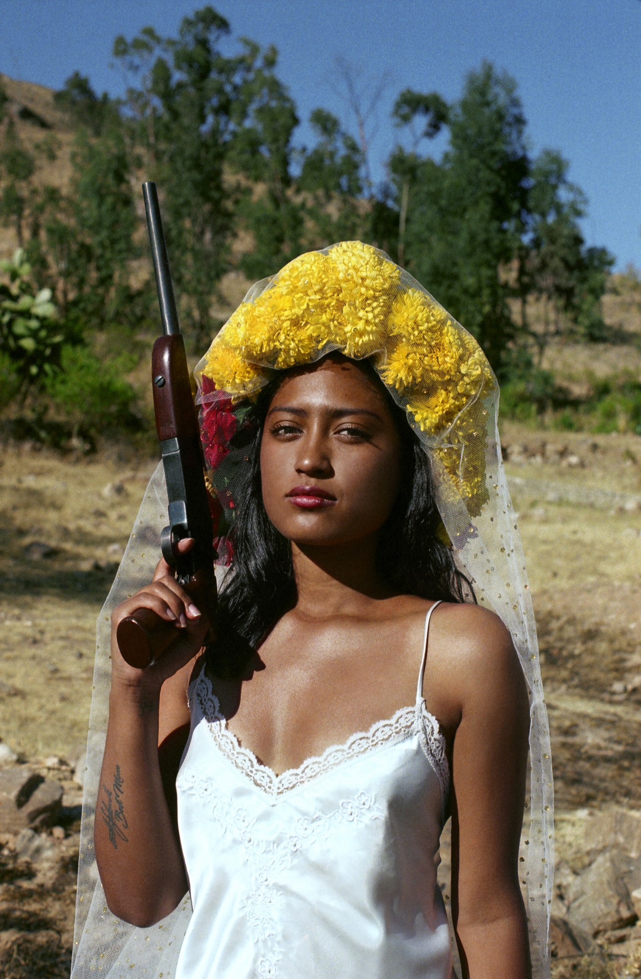 a girl in a white veil and nightgown holding a gun