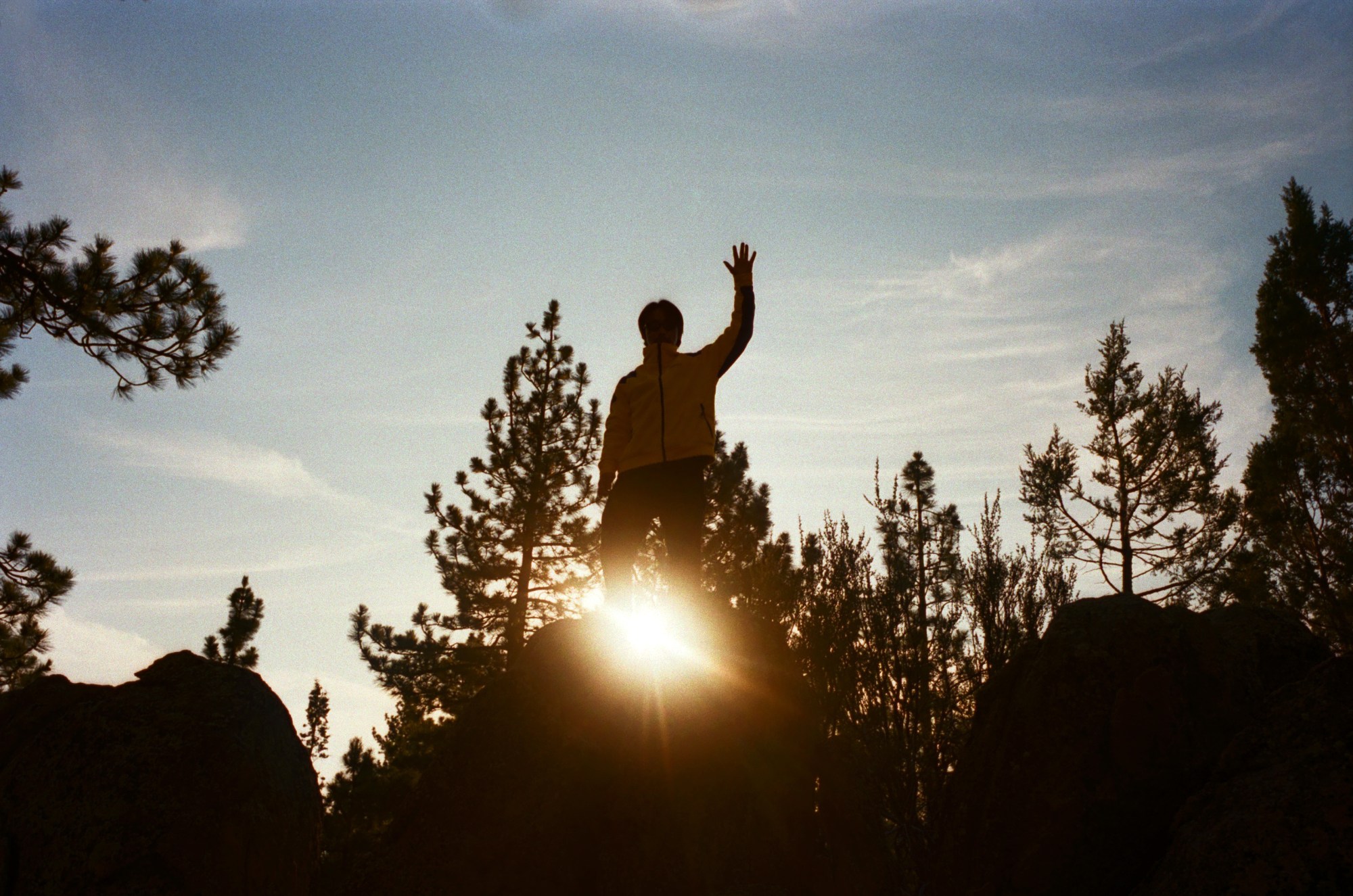 a photo of someone stood on top of a rock waving in a marmot jacket