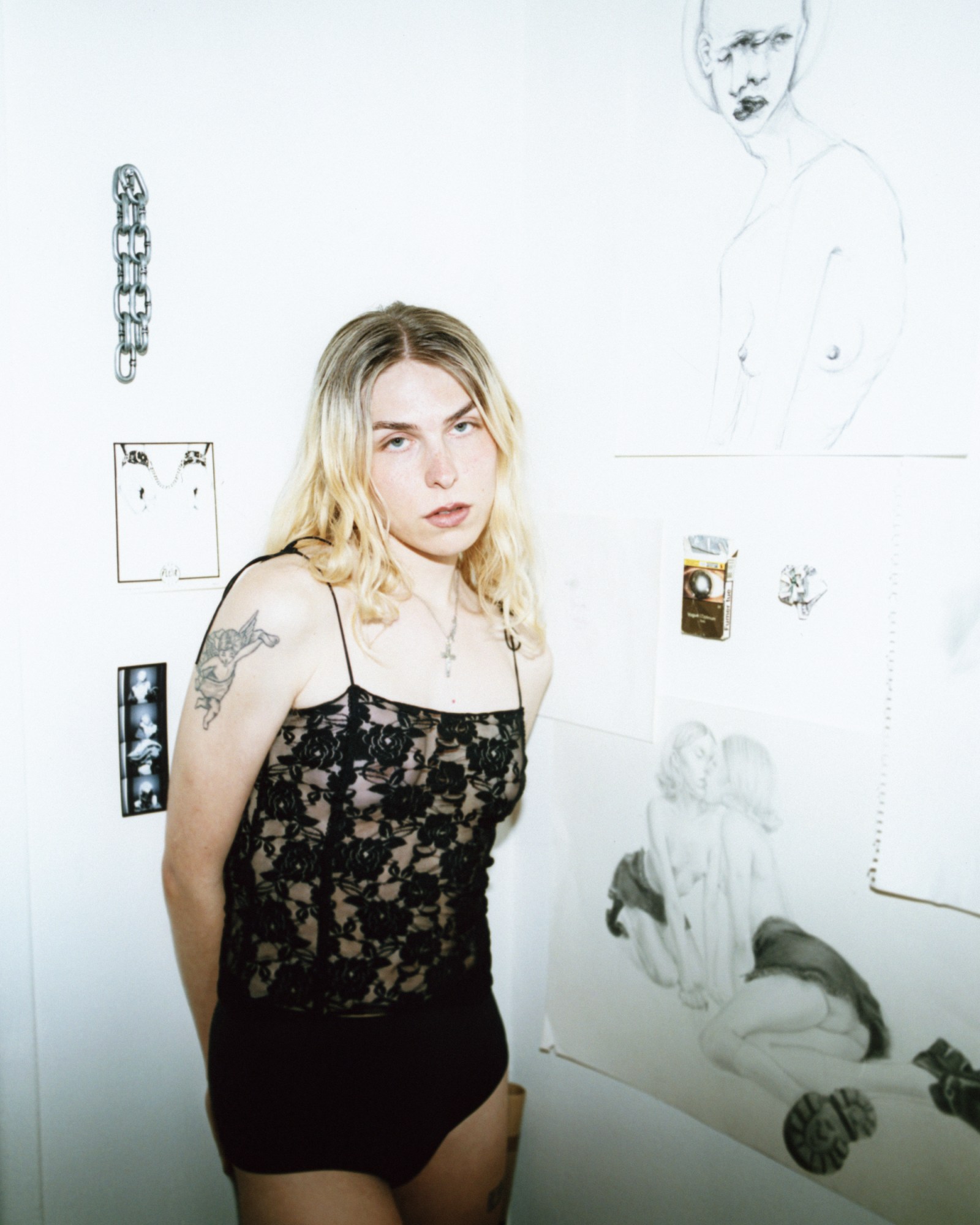 andi carter standing in front of drawings wearing black lace