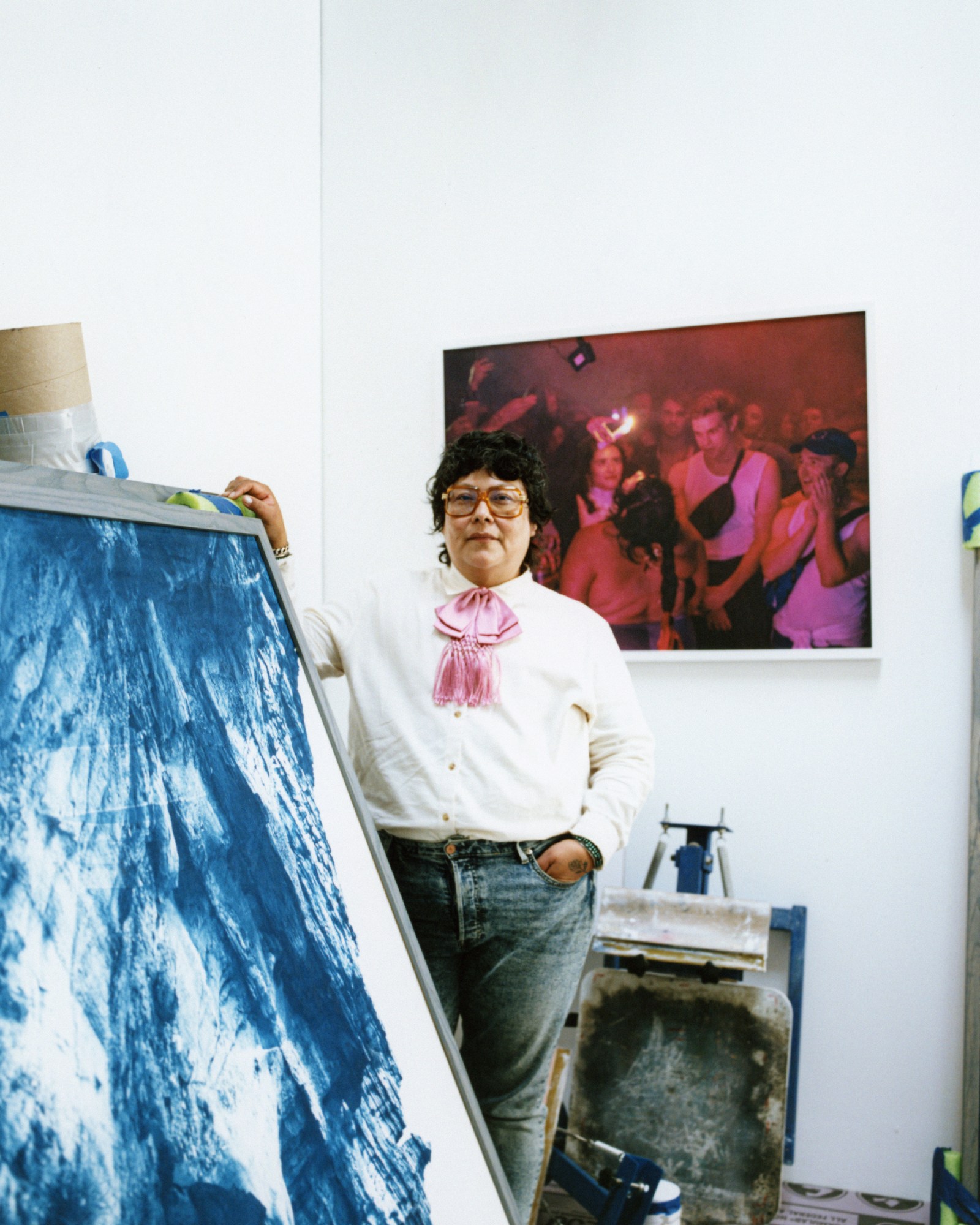 amina cruzholding a blue painted photograph in her studio