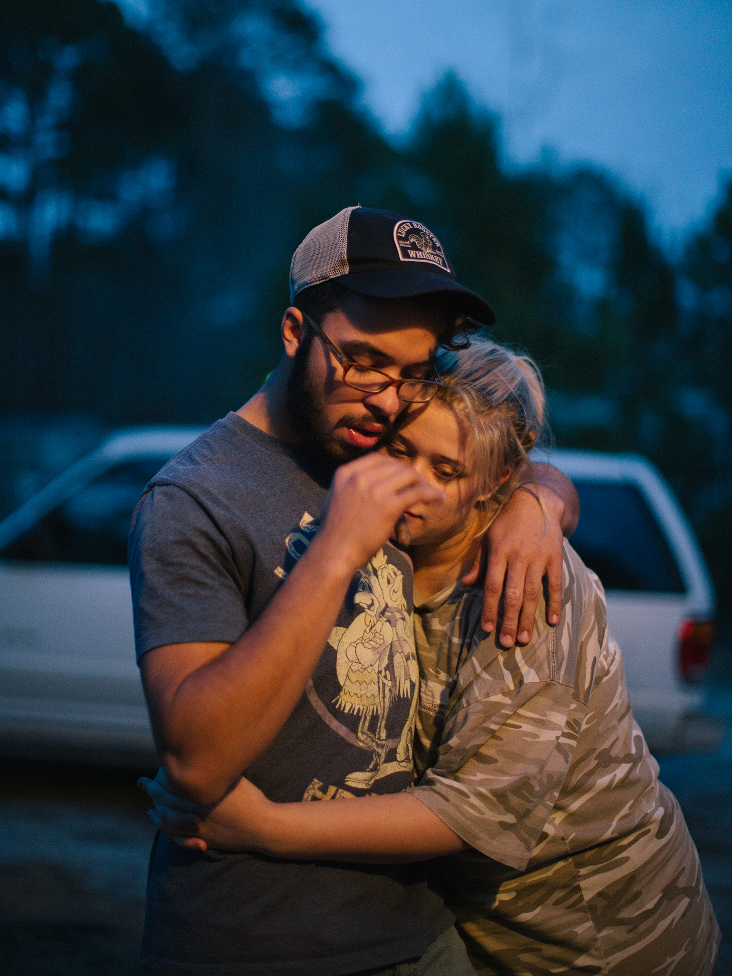 Manny and Courtney embracing in graphic t-shirts and camouflage outside in north carolina by maria sturm