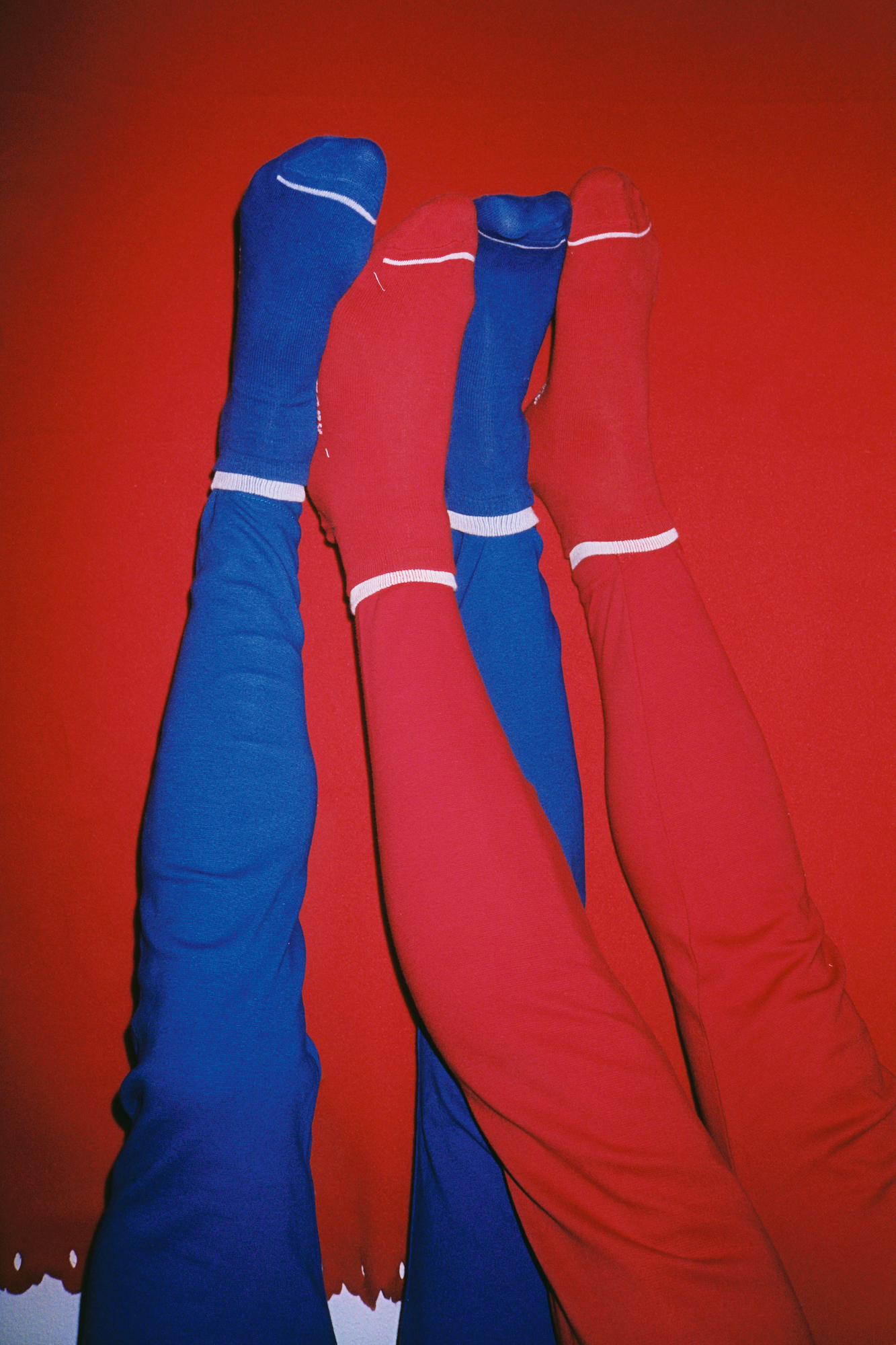 blue and red jeans and socks against a red wall