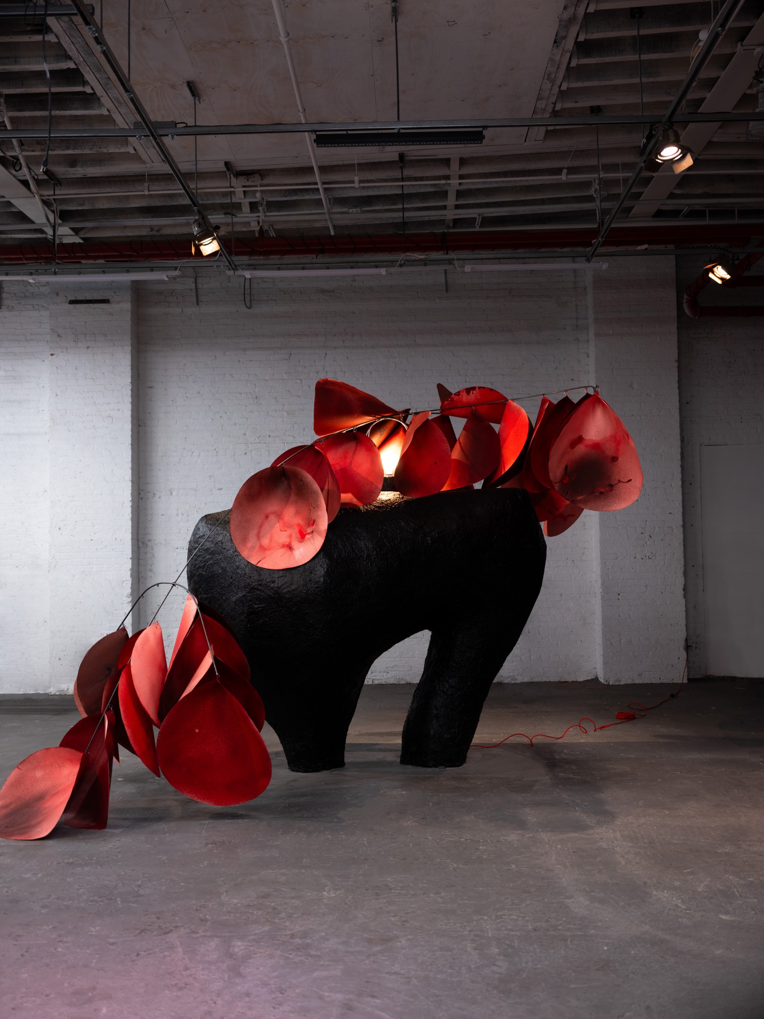 a welded sculpture by karina sharif with red paper petals