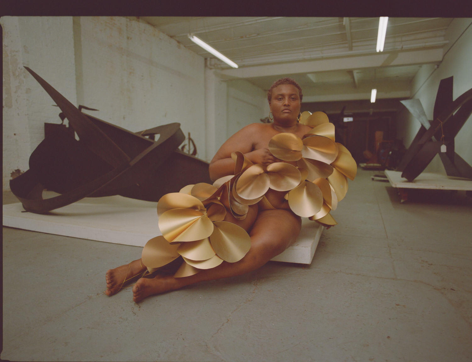 a model lying on a platform in gold paper art by karina sharif