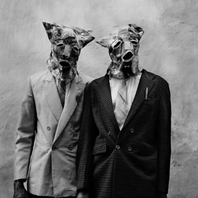 Photograph by Leah Gordon of two men in suits and bag masks at a haitian carnival