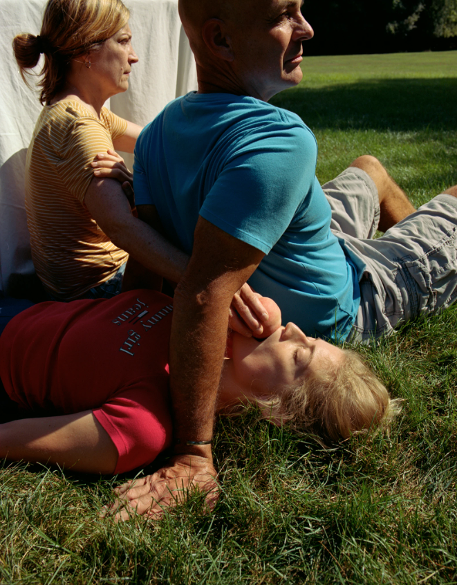 Photograph by Ashley Markle of a step-father, mother and daughter lying on the grass by a white sheet